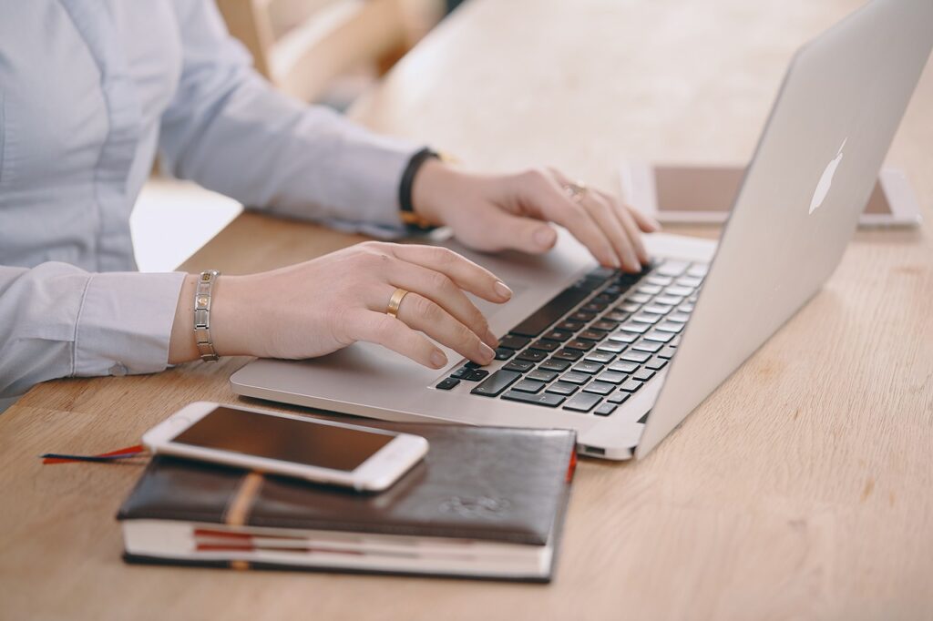 Mann am Notebook, mit Smartphone und Notizblock daneben, hier: Selbstständig machen