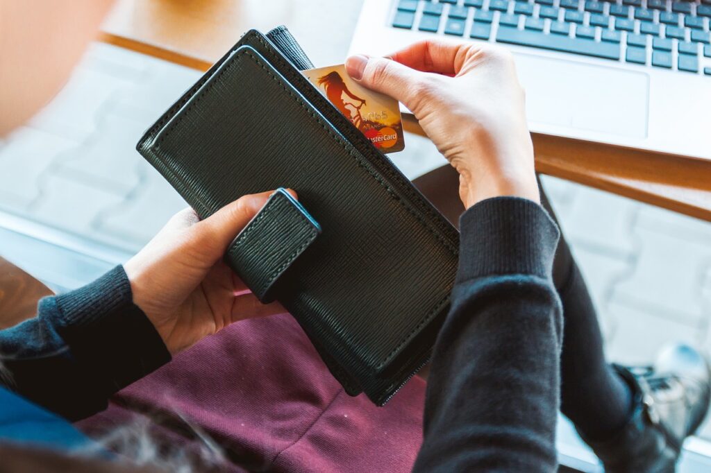 Portemonnaie mit Kreditkarte vor Notebook Tastatur gezückt, hier: Onlineshop eröffnen
